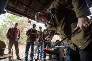 D.J. Johnson perfects the curve of a fireplace poker he and other Honors College students made under the watchful eye of blacksmith Andy Waller. Photo by Robert Jordan/Ole Miss Communications